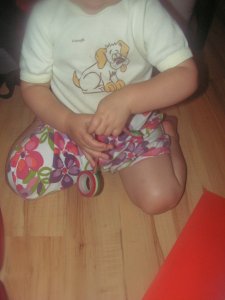 A lányom segít piros, fehér, zöld dekortapasszal körberagasztani a kartont.