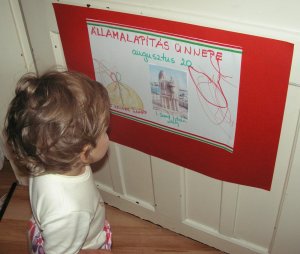 Elkészült a mű. A nappali ajtajára tettem ki, a lányom szemmagasságába. Meg is csodálta rögtön. Még rajzoltunk a tablónkra egy kenyeret, és felragasztottunk egy istvános képet. 